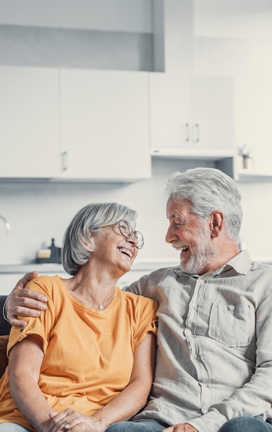 Photo un mari et une femme mûrs heureux s'assoient et se reposent sur le canapé à la maison en s'étreignant et en se caressant, en montrant de l'affection, en souriant, en étant âgés, en s'aimant, en se relaxant sur le canappé, en samusant, en profitant d'un week-end familial tendre et romantique.