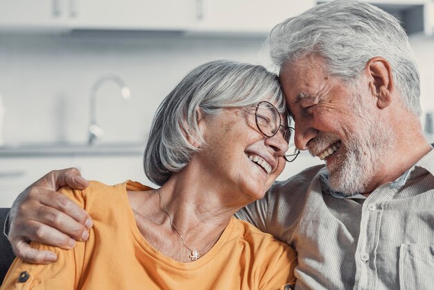 Photo un mari et une femme mûrs heureux s'assoient et se reposent sur le canapé à la maison en s'étreignant et en se caressant, en montrant de l'affection, en souriant, en étant âgés, en s'aimant, en se relaxant sur le canappé, en samusant, en profitant d'un week-end familial tendre et romantique.