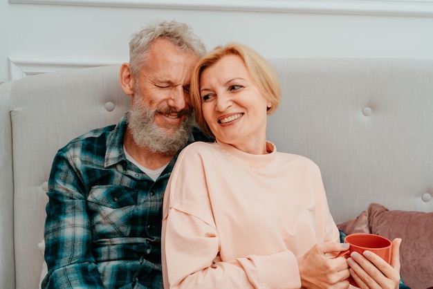 Le mari et la femme prennent le petit déjeuner avec du café sur le lit à la maison