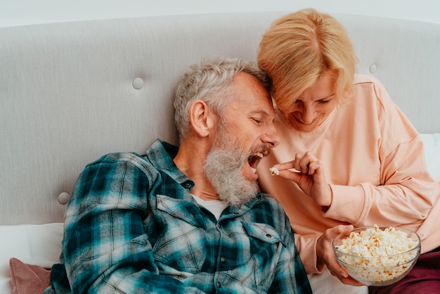 Mari et femme regardent un film sur le lit et mangent du pop-corn