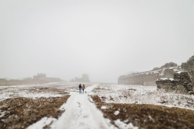 Mari et femme traversent le parc en se tenant la main en hiver.