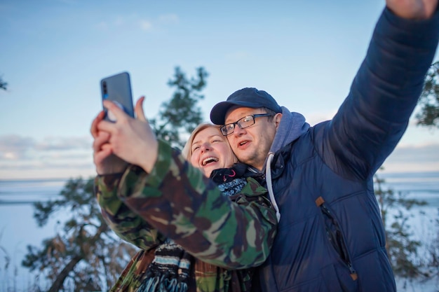 Mari et femme en veste militaire s'embrassent et font un selfie pour la mémoire pendant les vacances d'hiver saisonnières