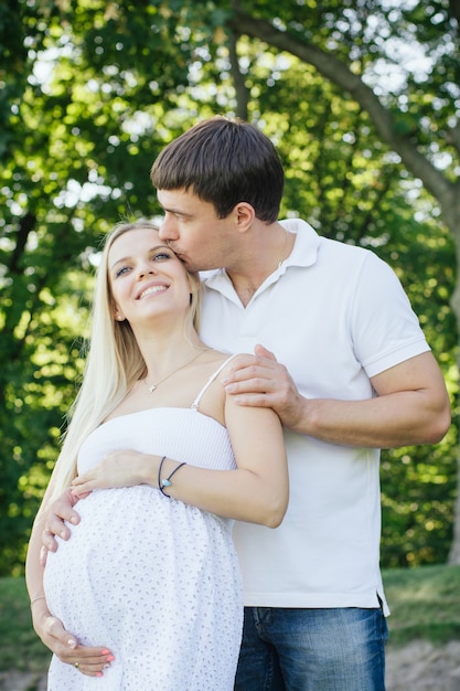 Un mari heureux embrasse sa femme enceinte. Des émotions positives pour une bonne santé.