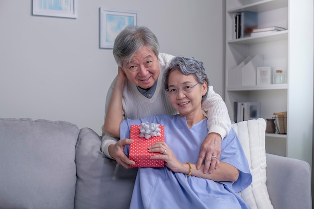 Mari homme senior asiatique donnant une boîte-cadeau pour la Saint-Valentin à une femme surprise heureuse.