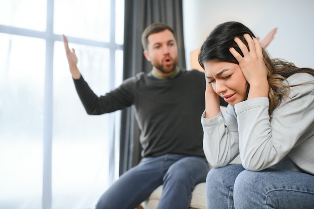Le mari irrité crie à sa femme avec violence La femme se couvre le visage de peur