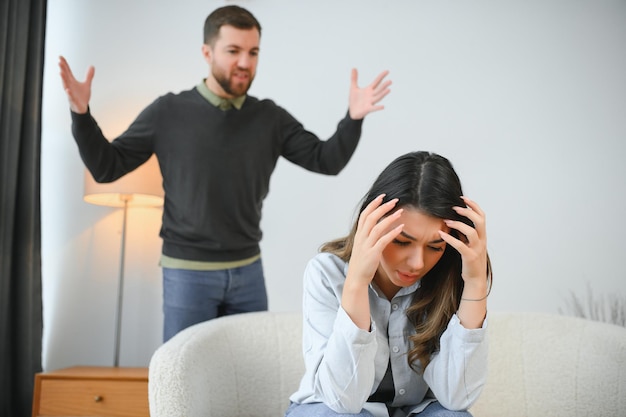 Le mari irrité crie à sa femme avec violence La femme se couvre le visage de peur