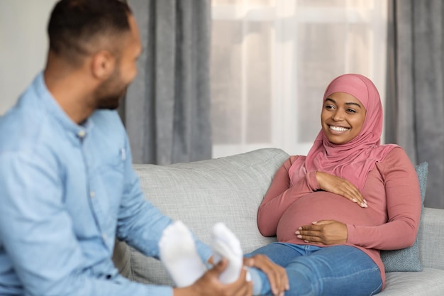 Mari noir aimant faisant un massage des pieds pour une femme musulmane enceinte à la maison