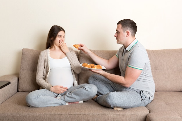 Le mari offre des croissants à sa femme enceinte