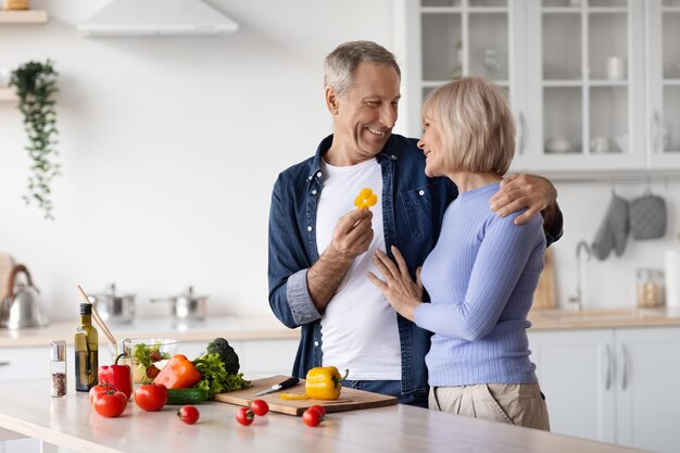 Mari senior aimant nourrir sa jolie femme pendant la cuisson