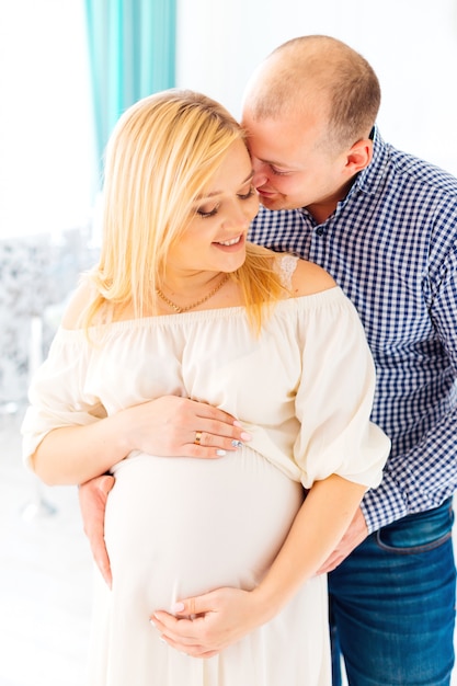 Un mari avec soin et tendresse embrasse sa femme enceinte