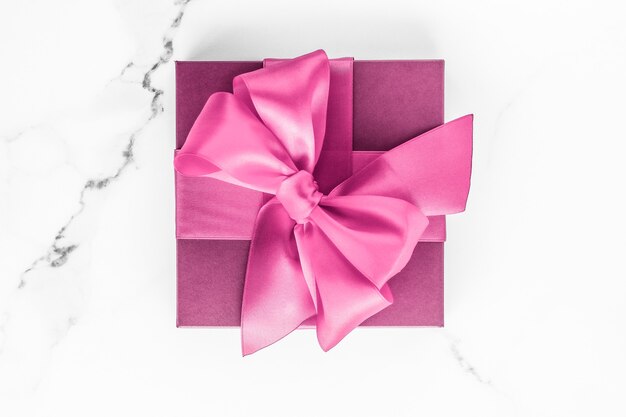 Mariage d'anniversaire et concept de marque girly coffret rose avec noeud en soie sur fond de marbre cadeau de douche de bébé fille et cadeau de mode glamour pour la conception d'art flatlay de vacances de marque de beauté de luxe