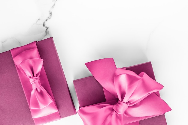 Mariage d'anniversaire et concept de marque girly coffret rose avec noeud en soie sur fond de marbre cadeau de douche de bébé fille et cadeau de mode glamour pour la conception d'art flatlay de vacances de marque de beauté de luxe