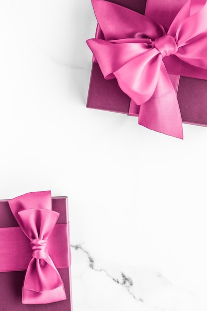 Mariage d'anniversaire et concept de marque girly coffret rose avec noeud en soie sur surface en marbre cadeau de douche de bébé fille et cadeau de mode glamour pour la conception d'art flatlay de vacances de marque de beauté de luxe