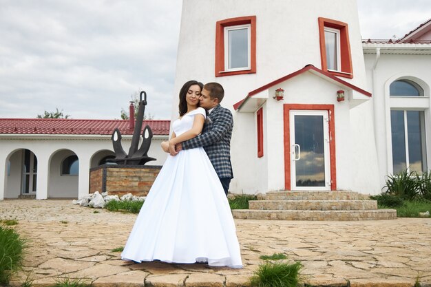 Mariage d'un couple amoureux dans la nature au phare. Câlins et bisous de la mariée et du marié