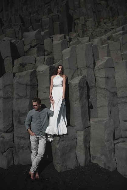 Mariage à destination de l'Islande. Un couple de mariés se promène le long de la plage noire de Vic.