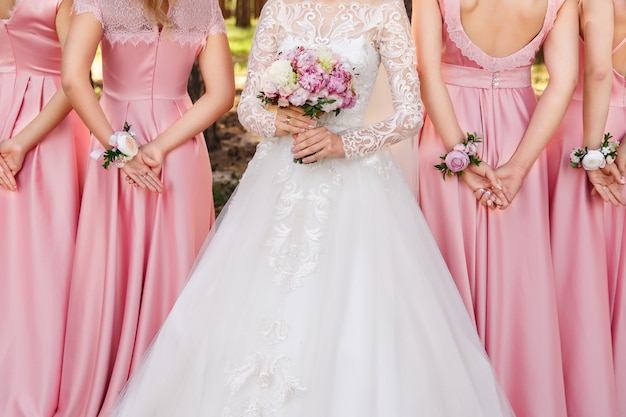 Mariage élégant et élégant. Mariée avec bouquet de mariée et demoiselles d'honneur avec de petits bouquets sur les bras. Robe de mariée blanche et robes de demoiselles d'honneur roses. Mariage conceptuel