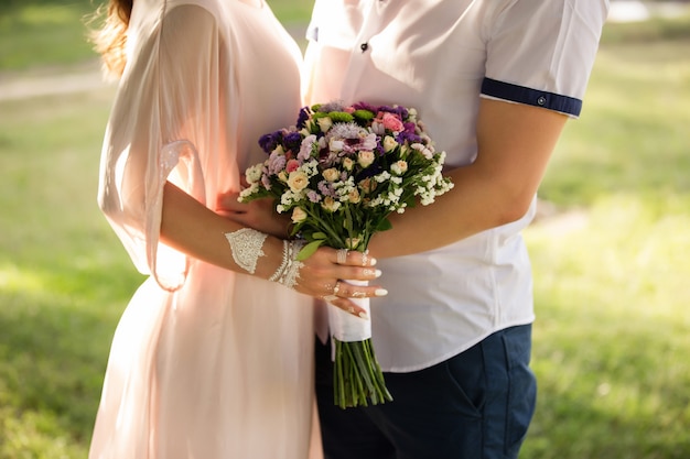 Mariage d'été, couple tenant le bouquet de fleurs.