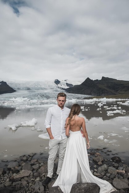 Mariage en Islande. Un gars et une fille en robe blanche s'étreignent debout sur une glace bleue