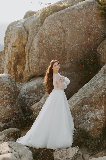 Mariage. Jeune belle mariée avec coiffure et maquillage posant en robe blanche.