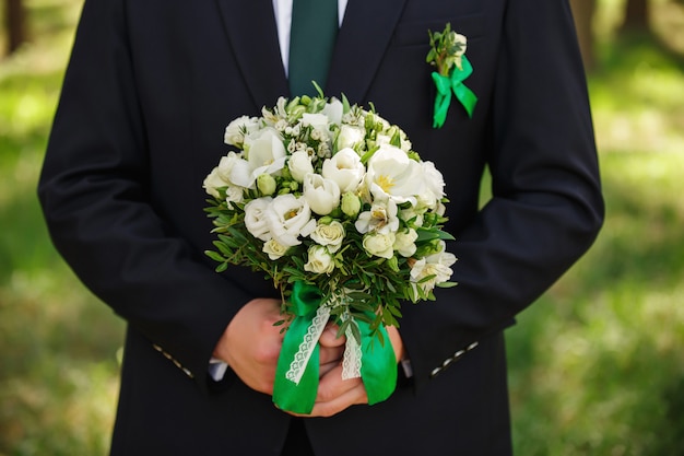 Mariage, marié tenant un bouquet de fleurs fraîches. Concept de mariage vert