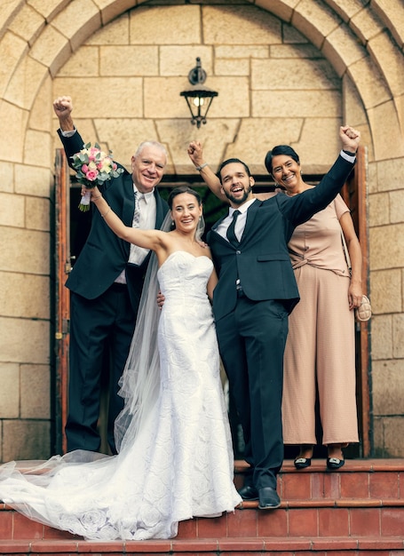 Mariage mariée et le marié avec les parents dans les escaliers de l'église et le bonheur lors d'une célébration excitée Couple de mariage et célébrer avec un portrait de fleurs et une famille heureuse pour l'amour avec maman papa et en plein air