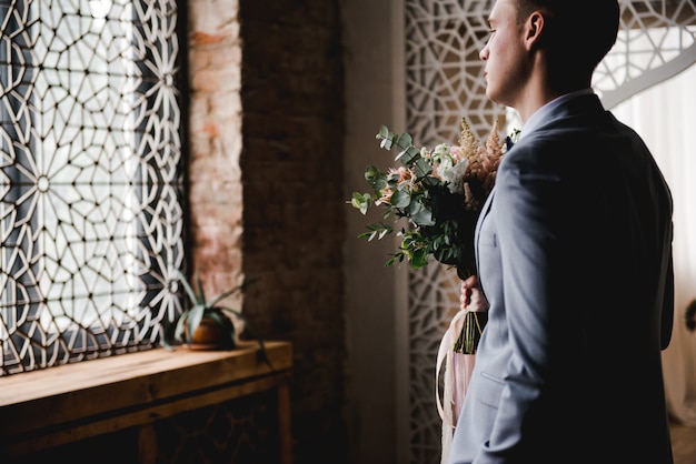 Le marié attend la mariée dans un costume gris.