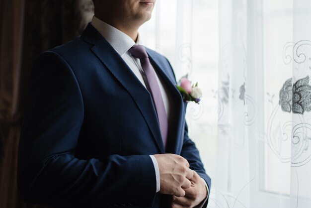 Photo le marié boutonne sa veste le marié dans une veste le jour du mariage