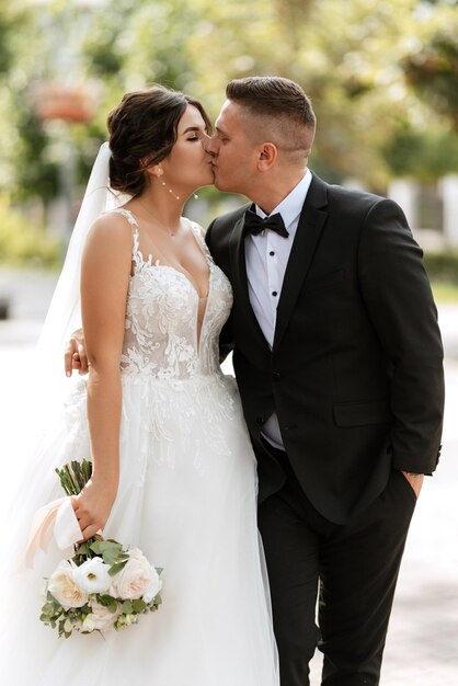 Photo le marié en costume brun et la mariée en robe blanche.