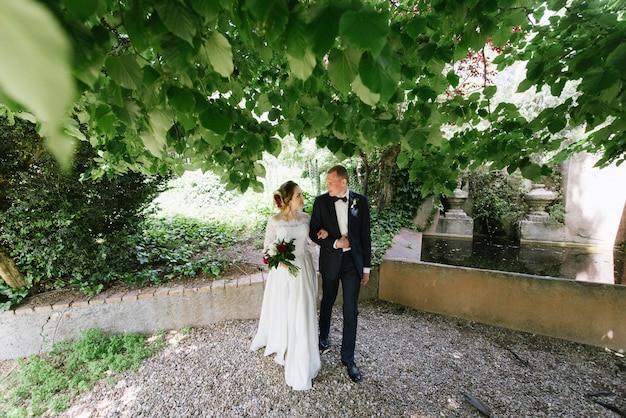 Le marié en costume et la mariée en robe de mariée se promènent dans le parc