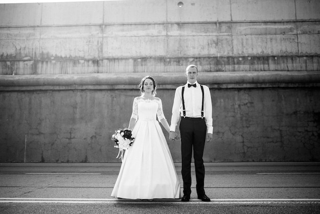 Le marié en costume et la mariée en robe de mariée sont sur la route