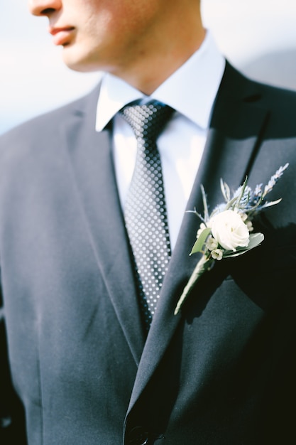 Marié dans une veste noire chemise blanche cravate à pois avec une boutonnière close up