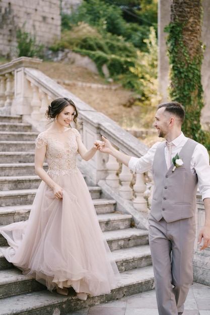 Le marié donne sa main à la mariée pour descendre les marches de pierre