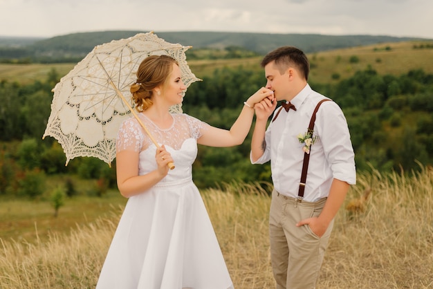 Le marié embrasse la main de la mariée contre un beau paysage