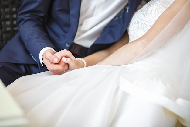 Le marié embrasse la mariée avec le bouquet de mariage entre les mains des jeunes mariés