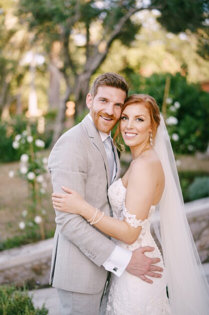 Le marié embrasse la mariée dans le parc verdoyant