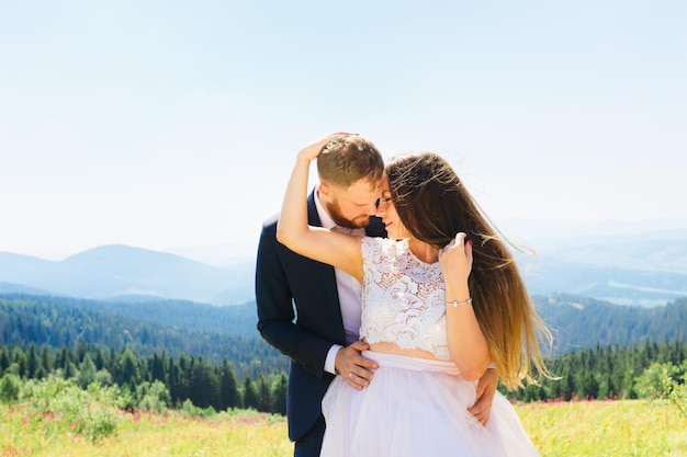 Le marié embrasse la mariée derrière la taille du côté de t