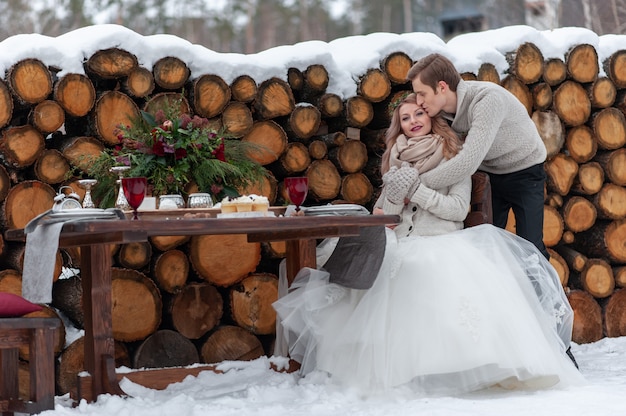 Photo le marié embrasse tendrement sa mariée de l'arrière sur fond de décoration de mariage d'hiver