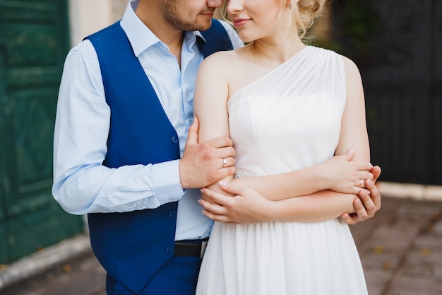 Le marié étreint doucement la mariée par derrière, la mariée croisa les bras