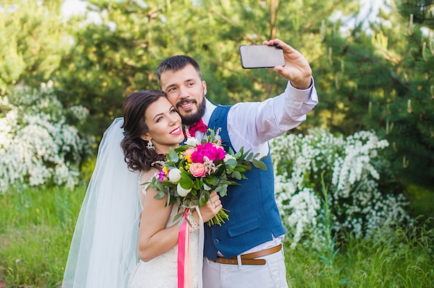 Le marié fait une photo avec sa mariée à l'extérieur