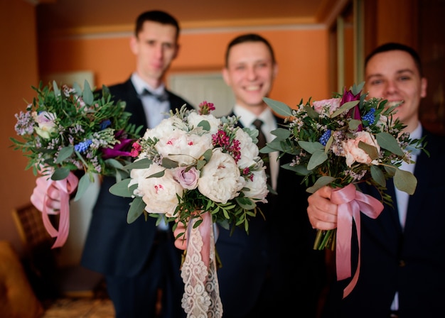 Le marié et les garçons d&#39;honneur tiennent la main avec des bouquets de mariage