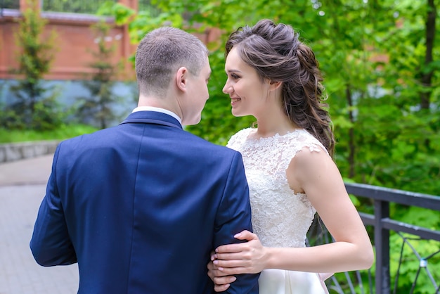 Le marié et la mariée belle debout et se regardant avec amour dans le parc d'été