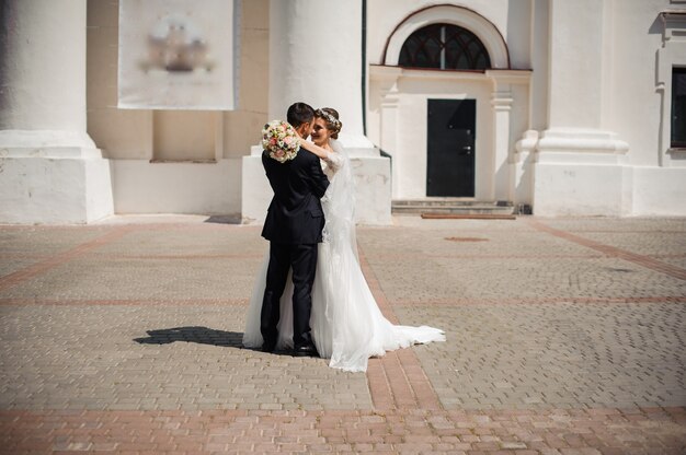 Le marié et la mariée avec un bouquet, un câlin dans la rue