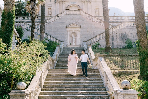 Le marié et la mariée descendent les marches d'une villa de luxe
