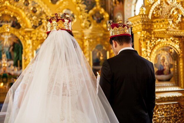 Le marié et la mariée font face à un autel à l'église. Tenant des bougies dans leurs mains