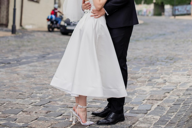 Le marié et la mariée en robe de mariée se tiennent ensemble dans la rue