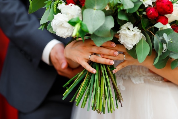 Le marié et la mariée tenant le bouquet de mariée