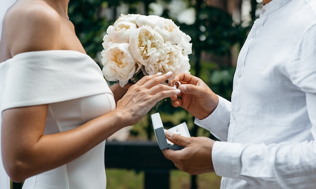 Le marié met la bague de mariage au doigt de la mariée