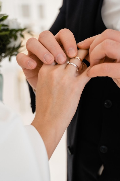 Le marié met la bague de mariage sur la bague de fiançailles de la mariée