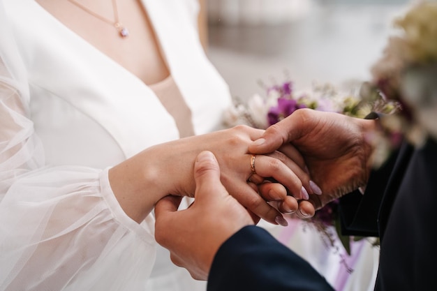 Le marié met la bague à la mariée gros plan échange de bagues