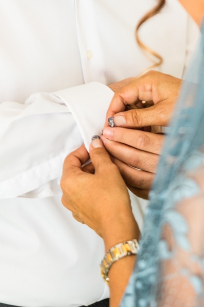 Un marié met des boutons de manchette alors qu&#39;il s&#39;habille le jour de son mariage. Costume du marié